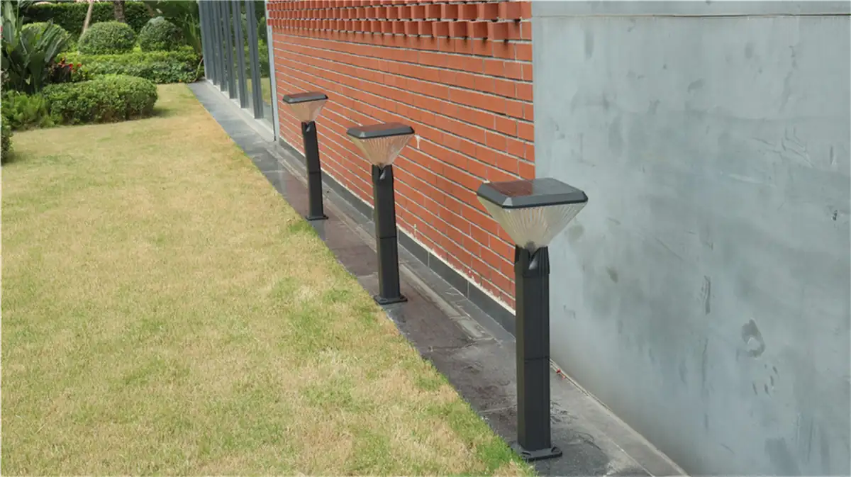 Square solar bollards along a brick wall and lawn