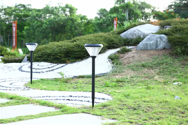 Low pathway fixtures beside planting and stone paving