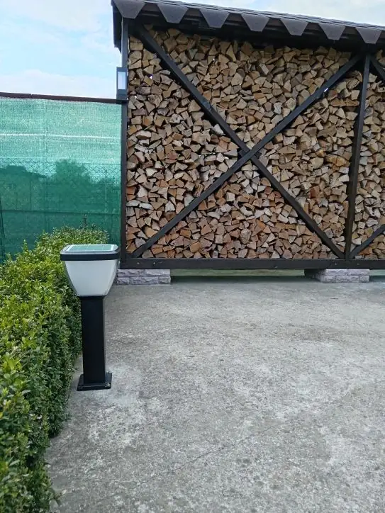 Bollard beside paving and a timber storage structure