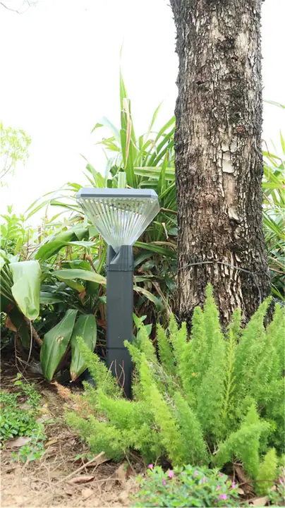 Low-level garden light beside a tree trunk and planting