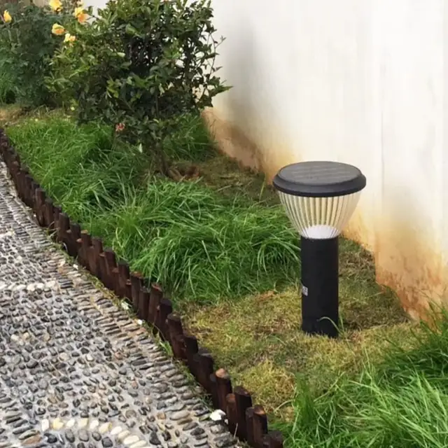 Bollard light in a planted border beside a wall and pebble path