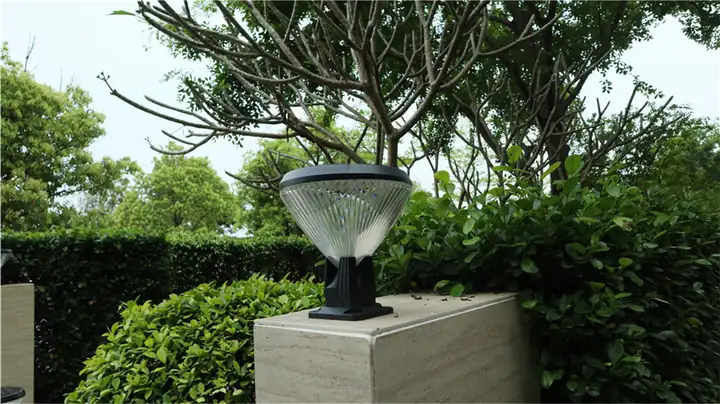 Solar pillar-top fixture on a garden wall beneath branches