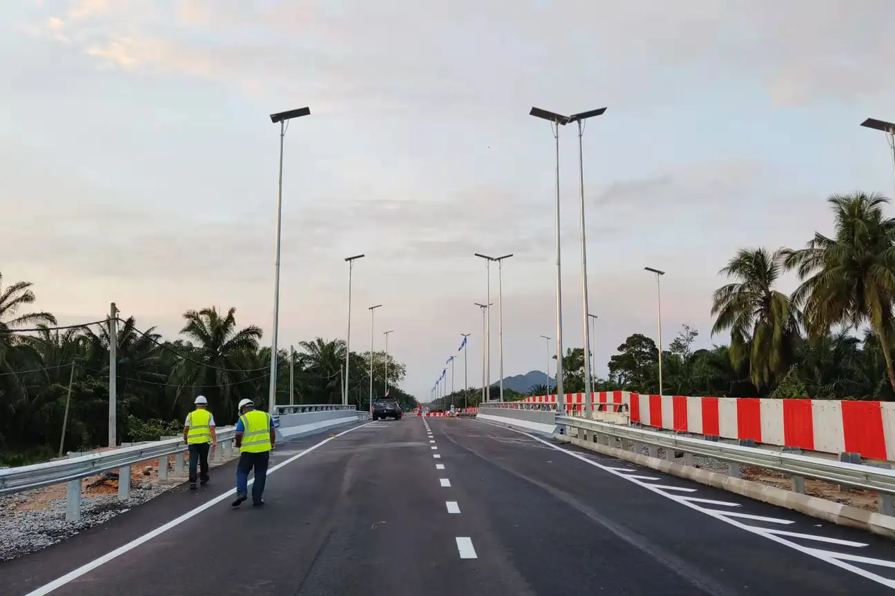 Solar street lights installed along a roadway with on-site workers.