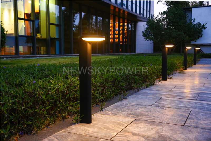 SLL-009 bollard lights along a paved path beside a hedge and building.