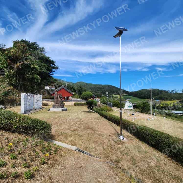 Solar street light beside a trimmed hedge on a landscaped slope