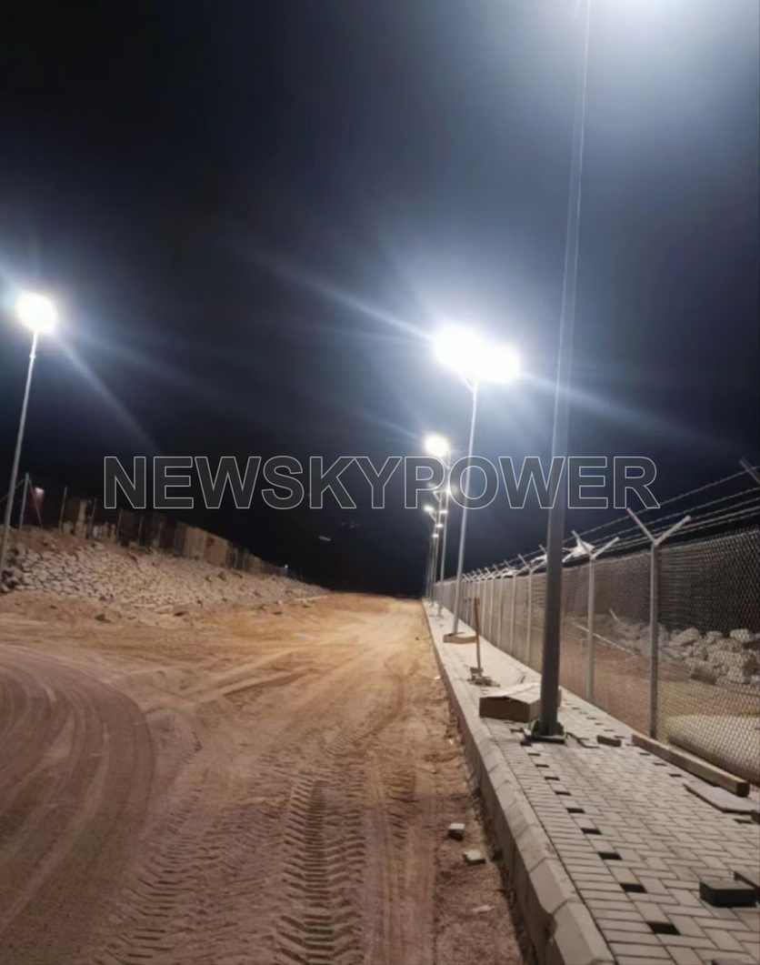 Street lights illuminated beside a fenced road at night